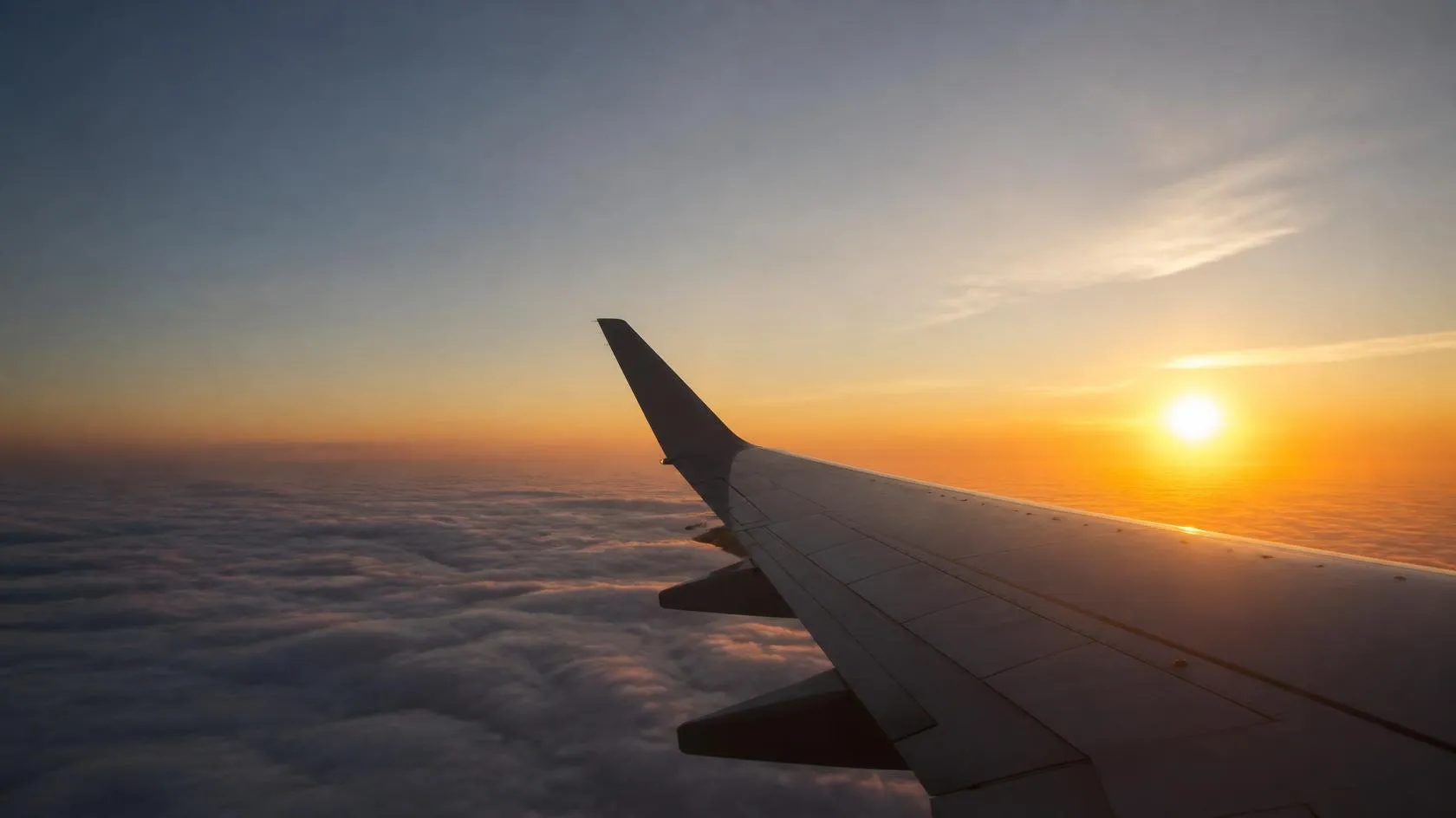 Aircraft wing above the clouds at sunset
