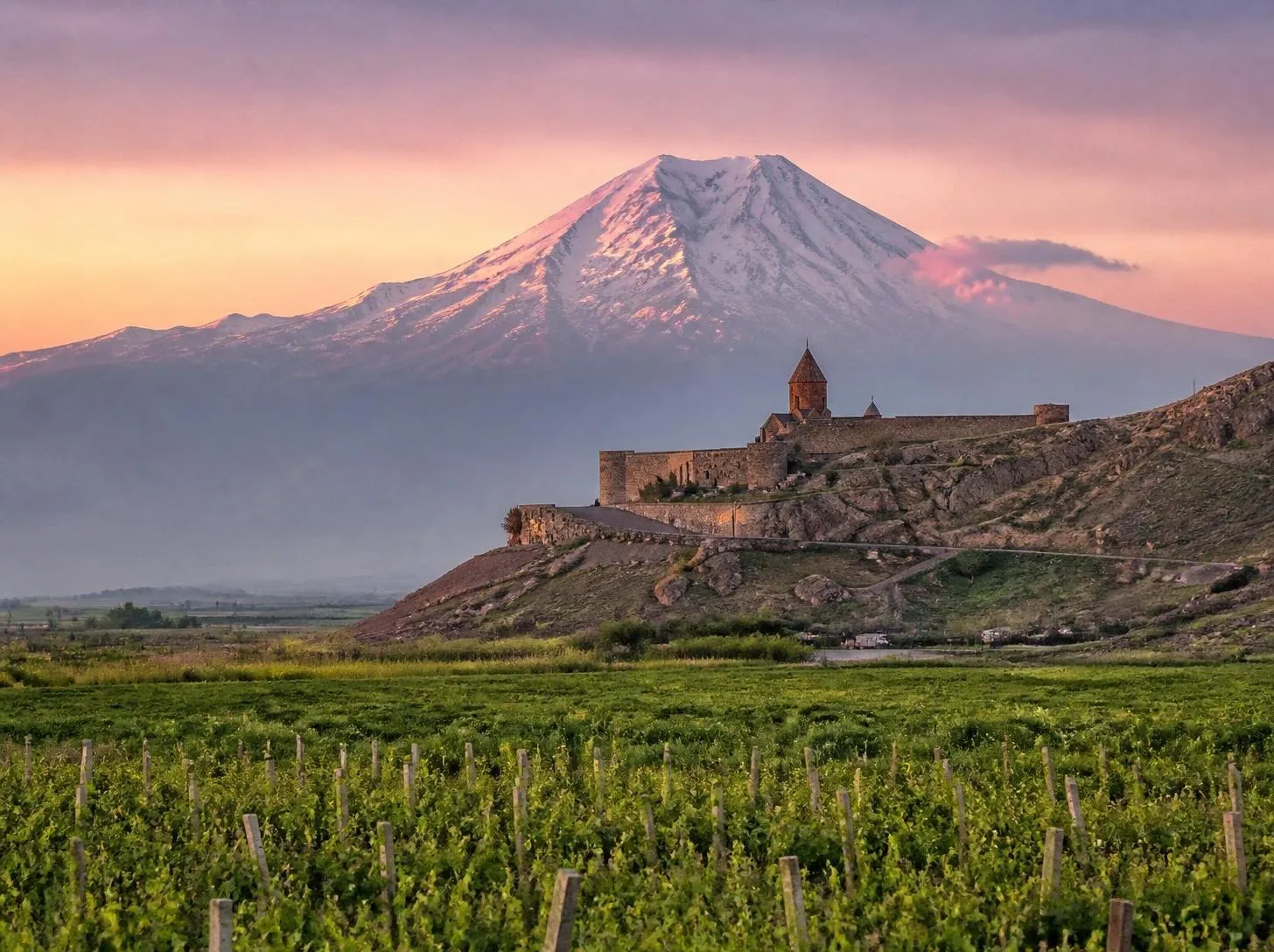 Ancient Armenian monastery with a snow-capped mountain at sunrise